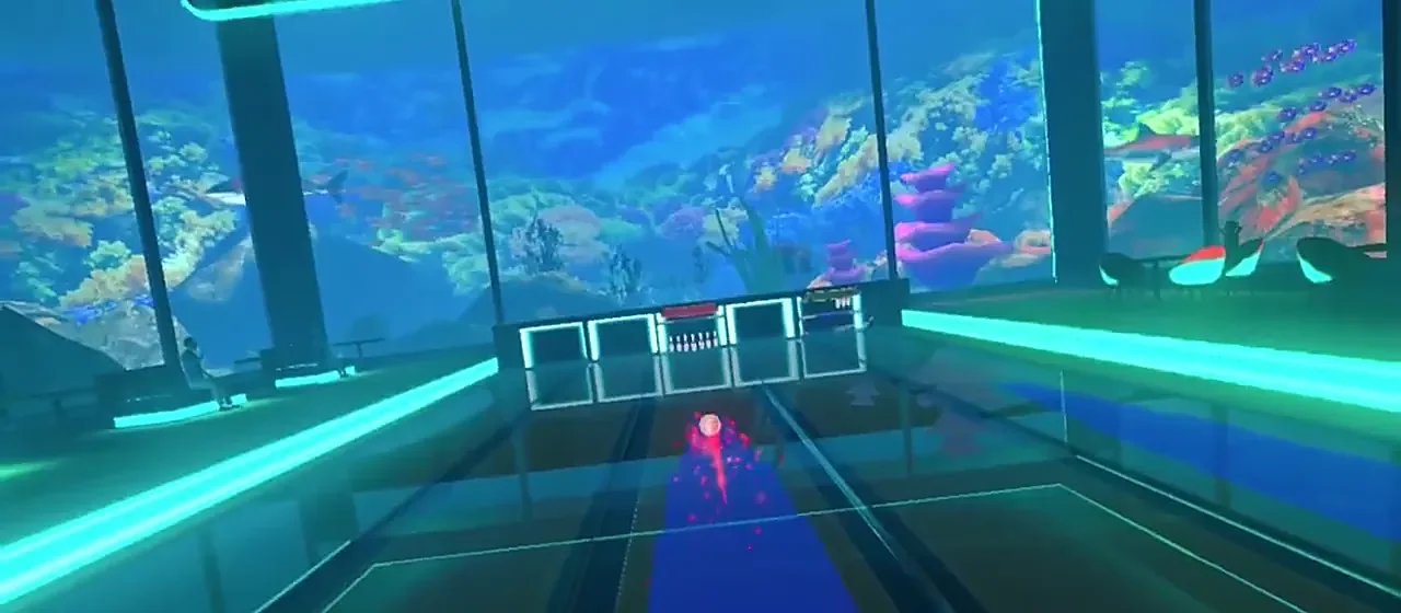 A ball rolls down a lane toward the pins in the Pearl arena, an aquarium behind the glass