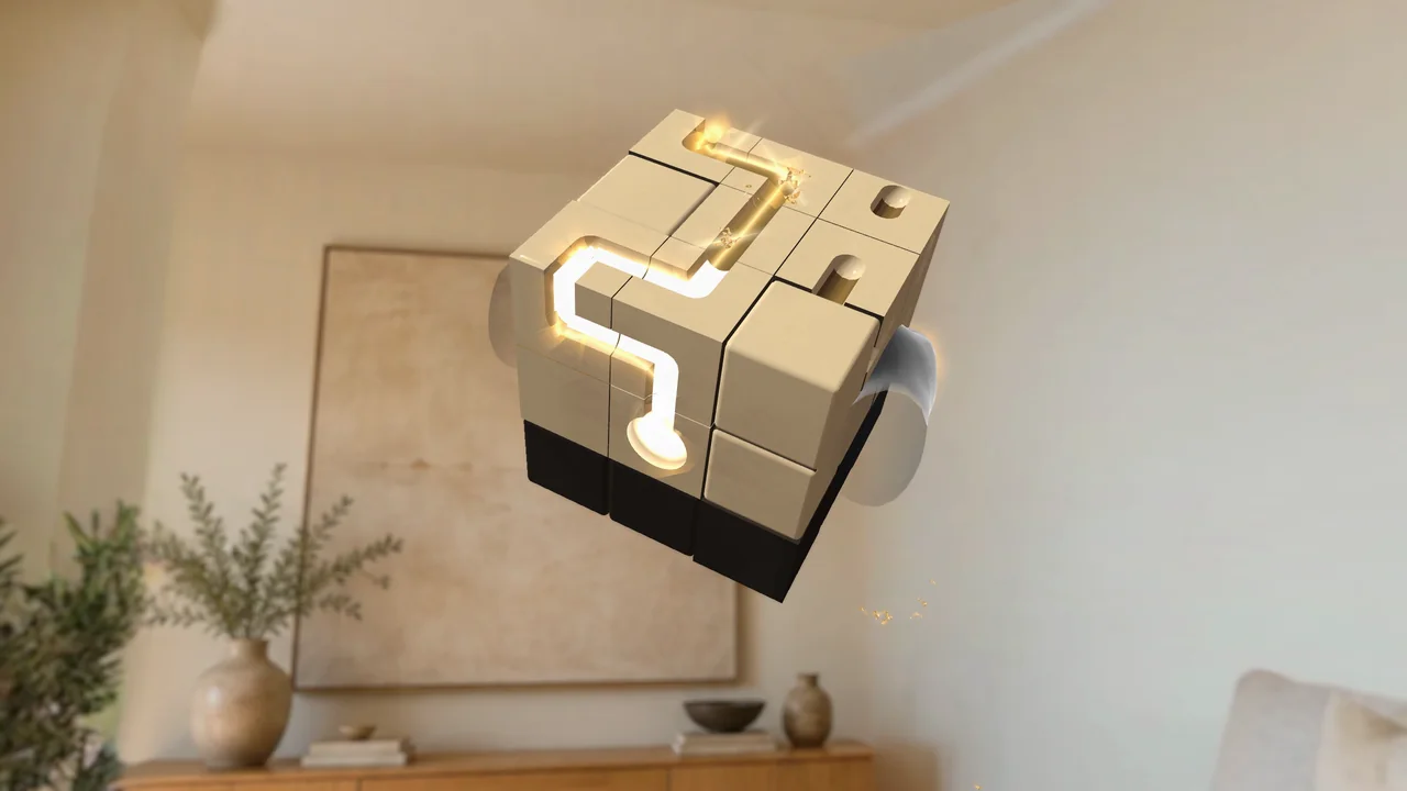 A marble drops into the glowing eye of a cream-and-black puzzle cube, and the path it took lights up in gold across the cube's face